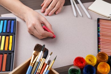 Artist drawing with chalk pastel at wooden table, closeup