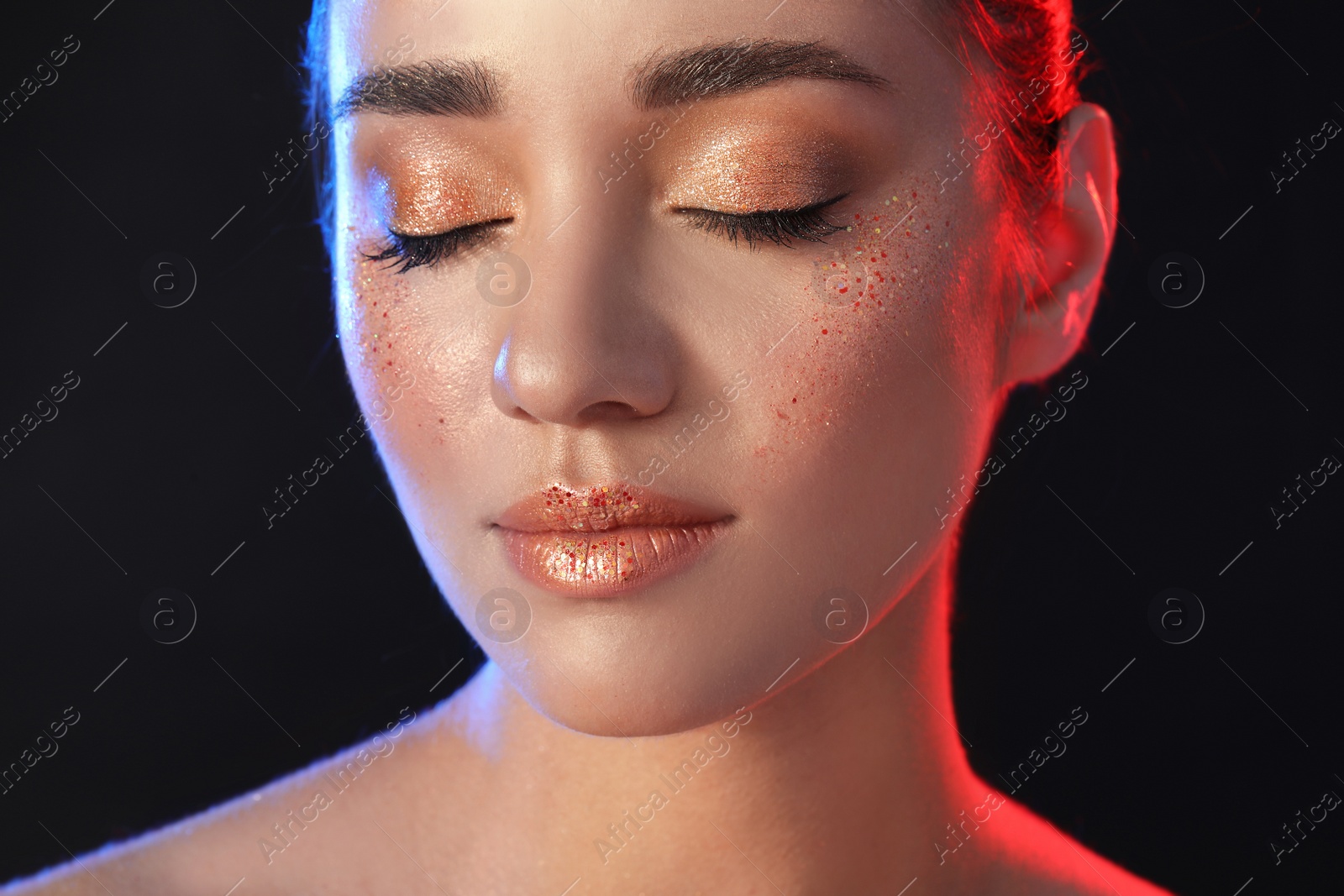 Photo of Beautiful young woman with glitter makeup on black background