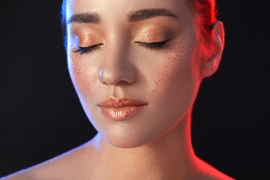 Beautiful young woman with glitter makeup on black background