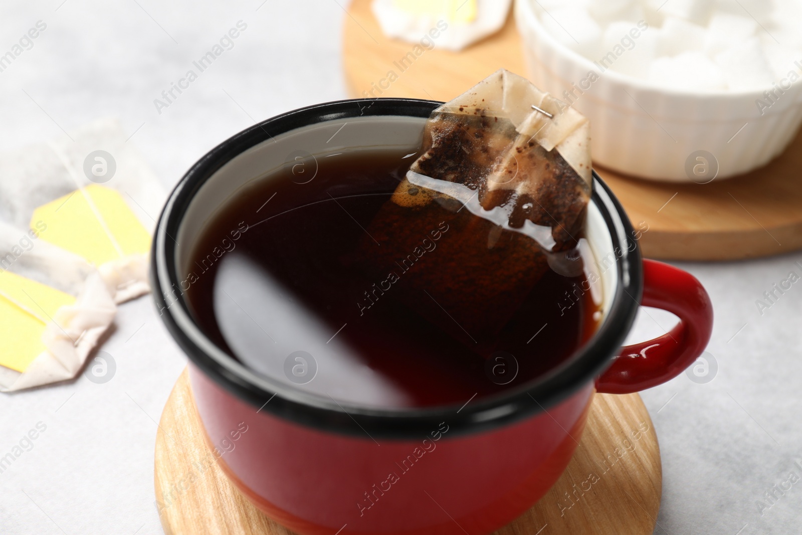 Photo of Brewing tea. Cup with tea bag on light table, closeup