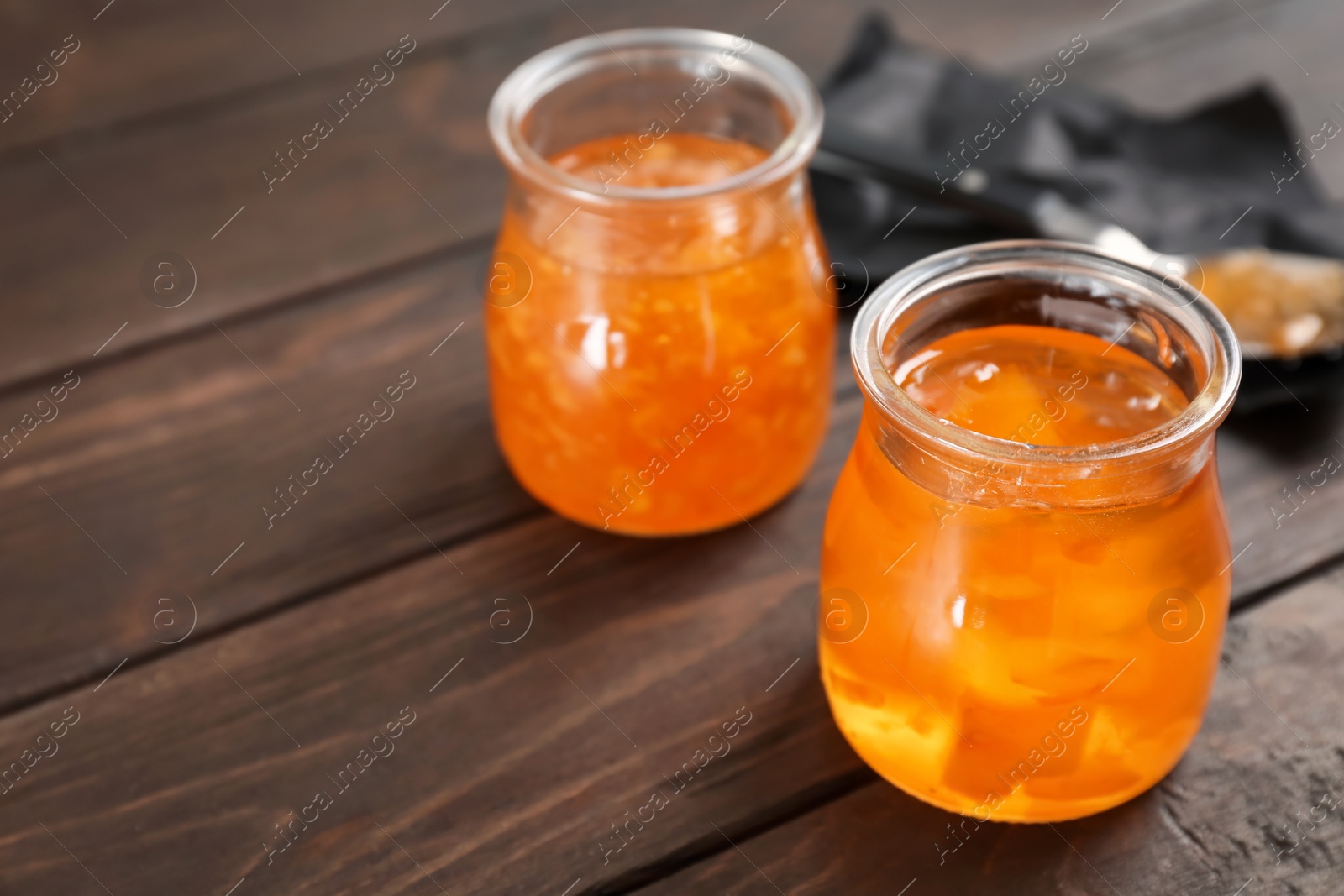 Photo of Jars with tasty sweet jam on wooden table