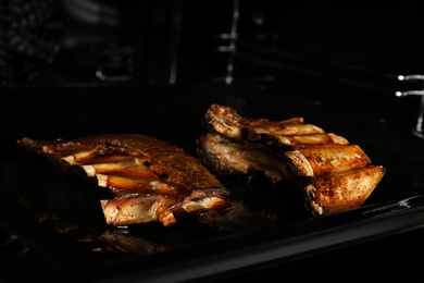 Photo of Delicious roasted ribs on baking sheet in oven