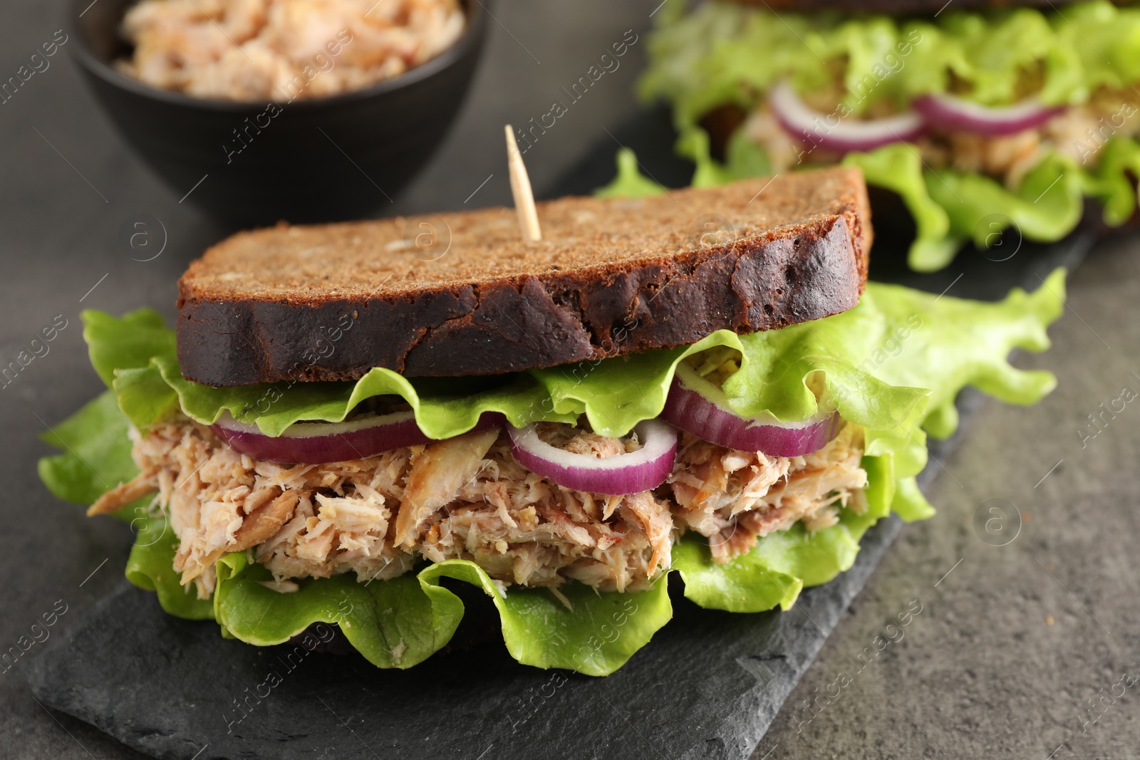 Photo of Delicious sandwiches with tuna and vegetables on light grey table, closeup