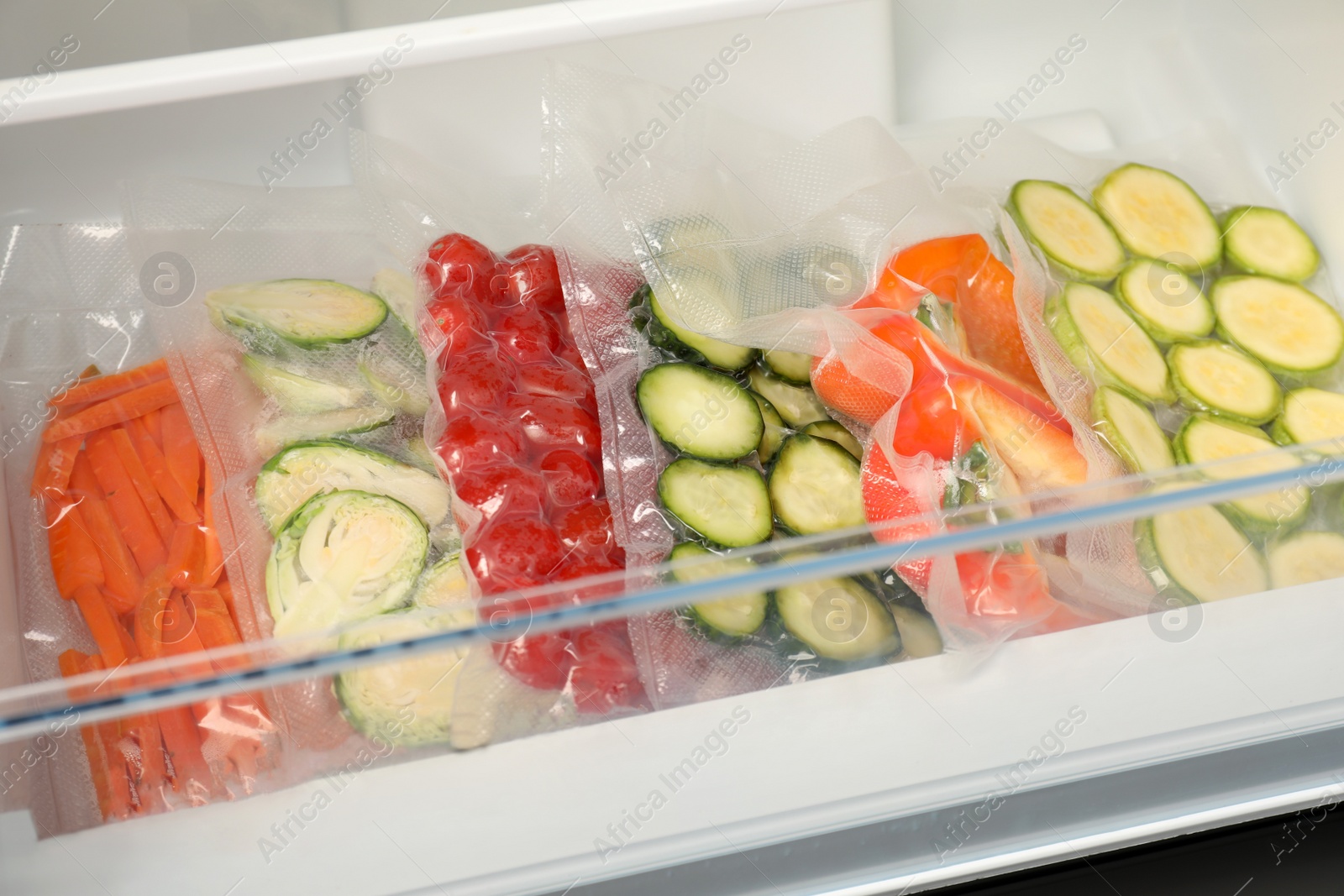 Photo of Vacuum bags with different vegetables in fridge. Food storage