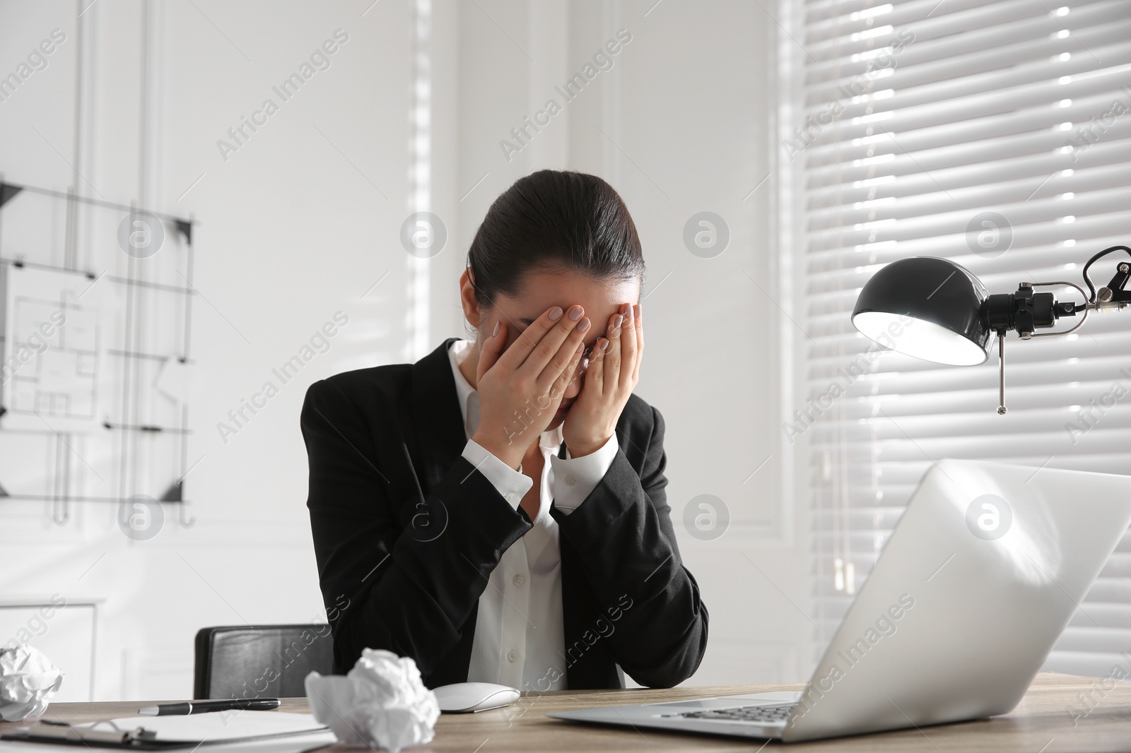 Photo of Stressed and tired young woman at workplace