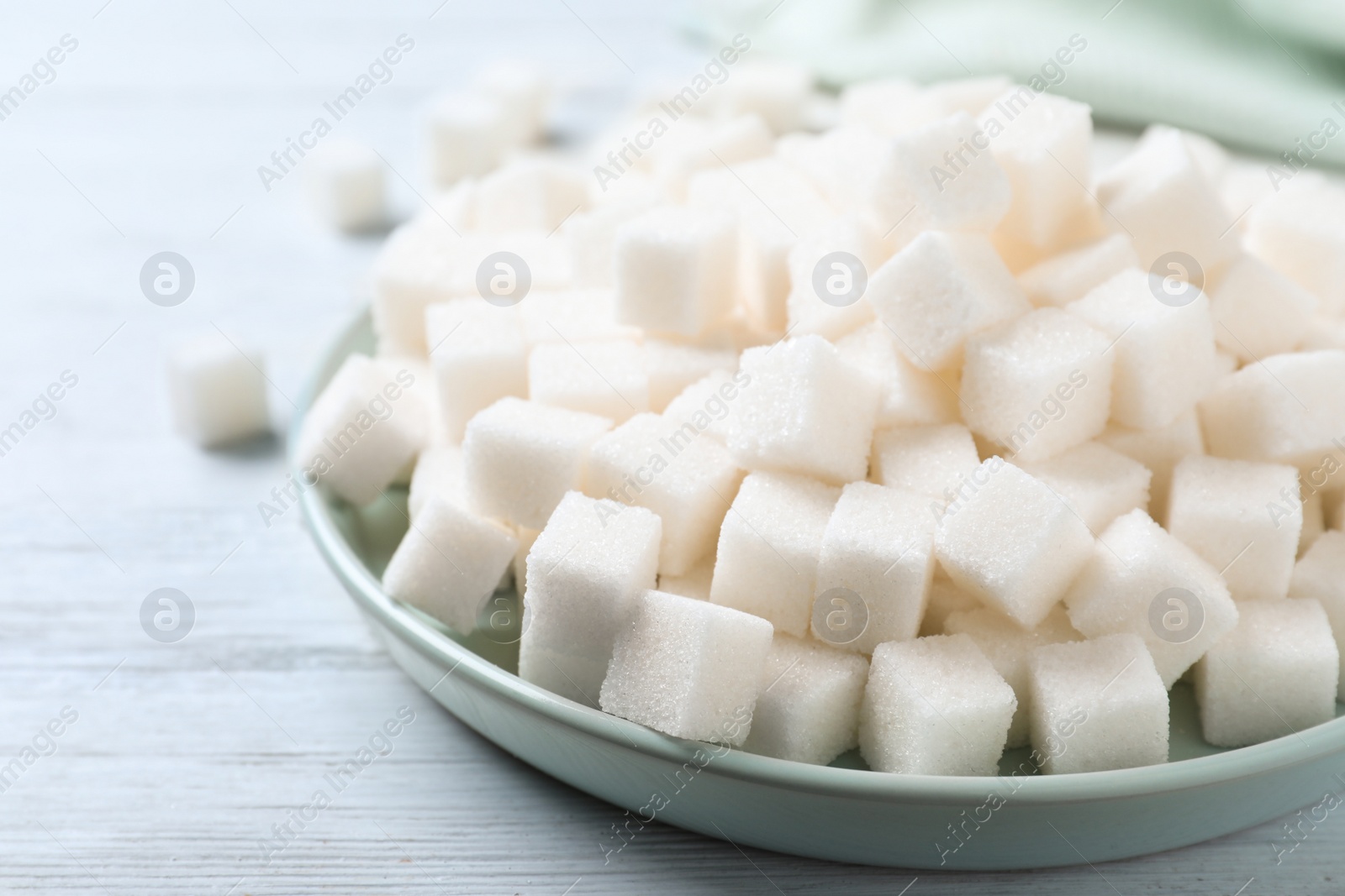 Photo of Refined sugar cubes on white wooden table, closeup