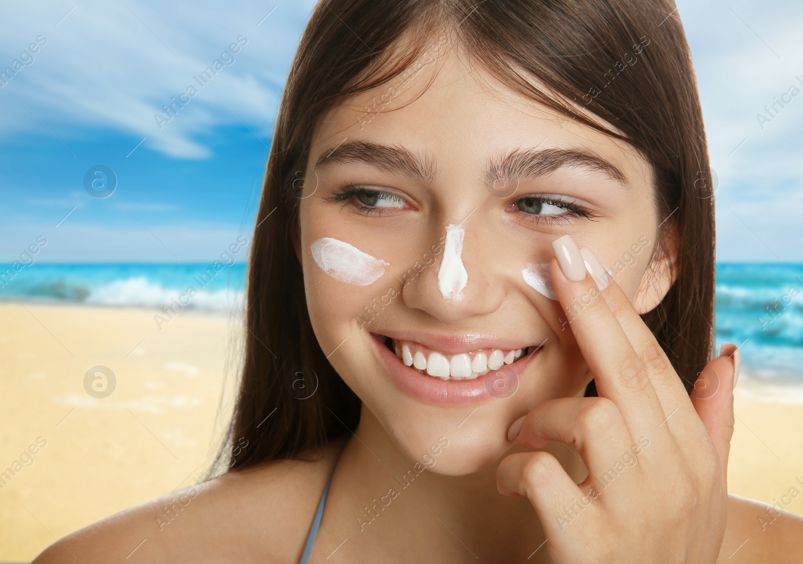 Image of Teenage girl with sun protection cream on her face near sea, closeup