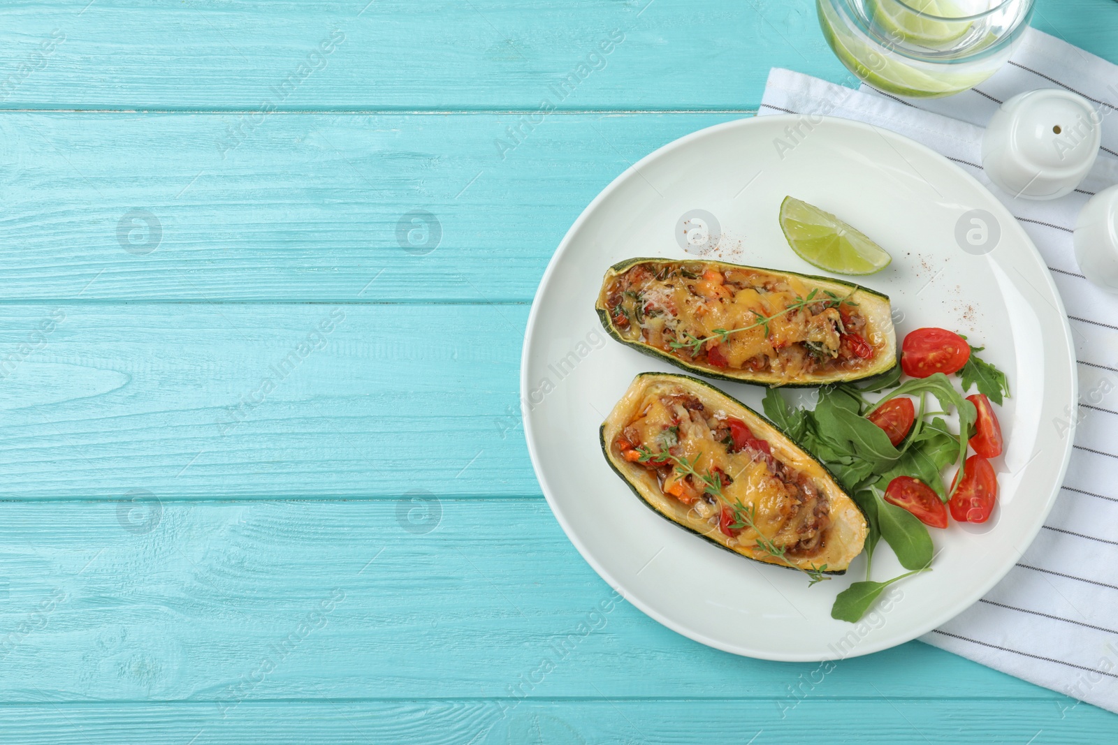 Photo of Flat lay composition with delicious stuffed zucchini on light blue wooden table. Space for text