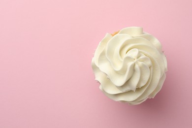 Photo of Tasty vanilla cupcake with cream on pink background, top view. Space for text