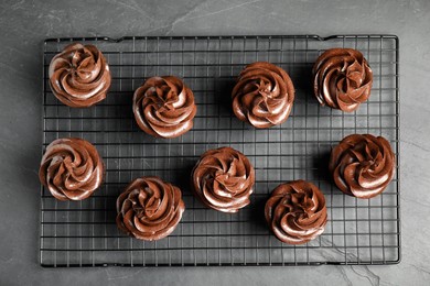 Cooling rack with delicious chocolate cupcakes on black table, top view