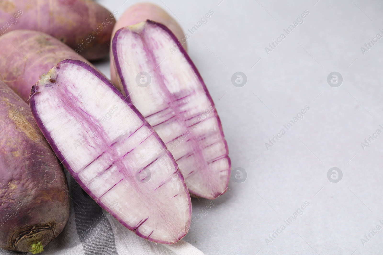 Photo of Purple daikon radishes on light grey table, closeup. Space for text