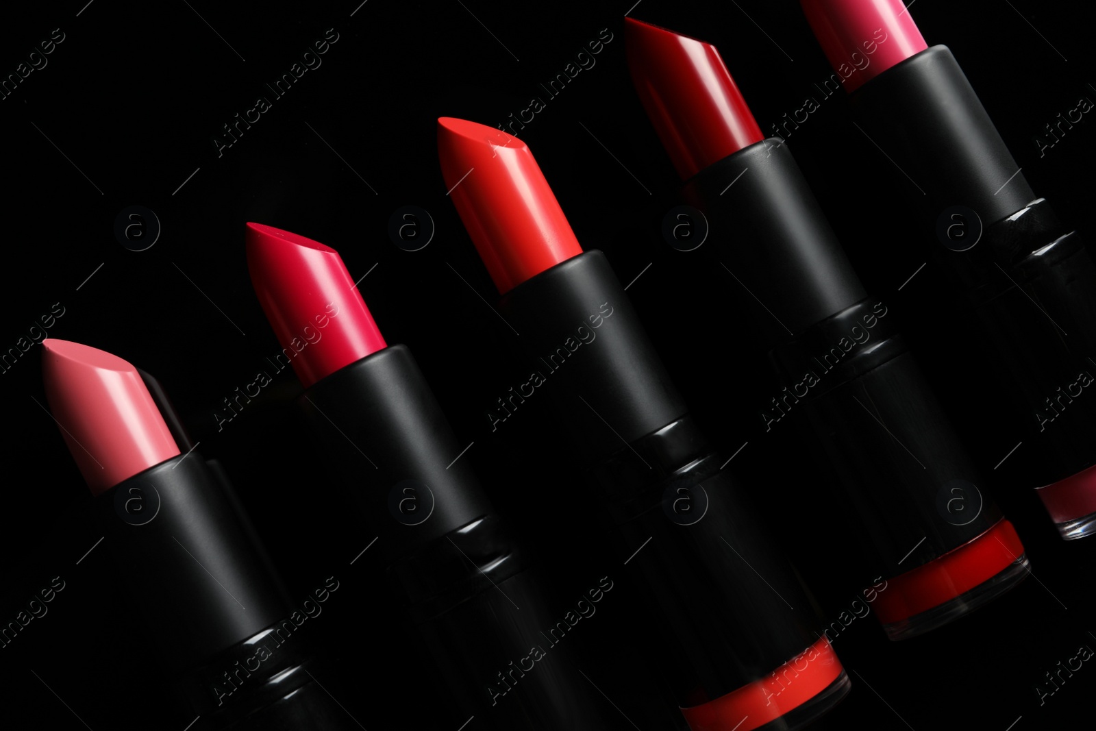 Photo of Many bright lipsticks on black background. Professional makeup product