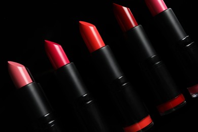 Photo of Many bright lipsticks on black background. Professional makeup product