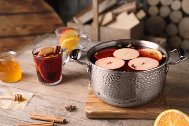 Photo of Delicious mulled wine and ingredients on wooden table