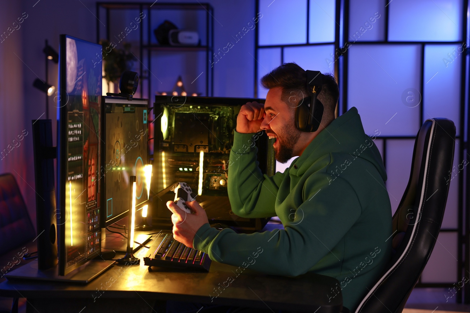 Photo of Man playing video games with controller at table indoors