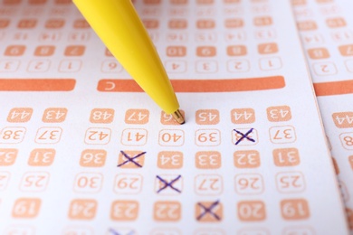 Filling out lottery ticket with pen, closeup