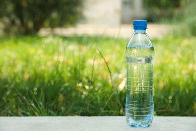 Bottle of fresh water outdoors. Space for text