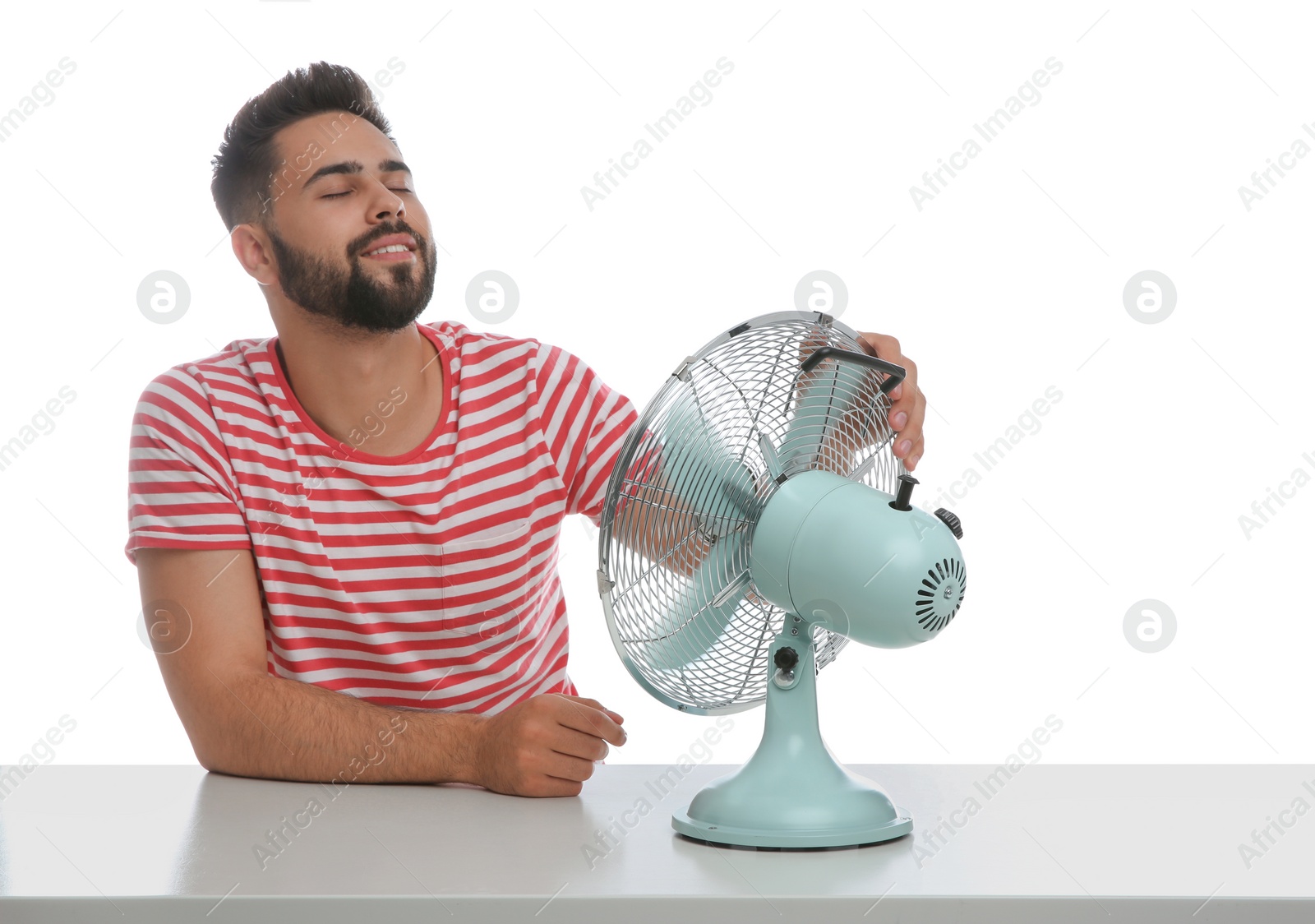 Photo of Man enjoying air flow from fan on white background. Summer heat