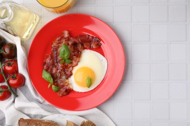 Photo of Fried egg and bacon served on white tiled table, top view. Space for text