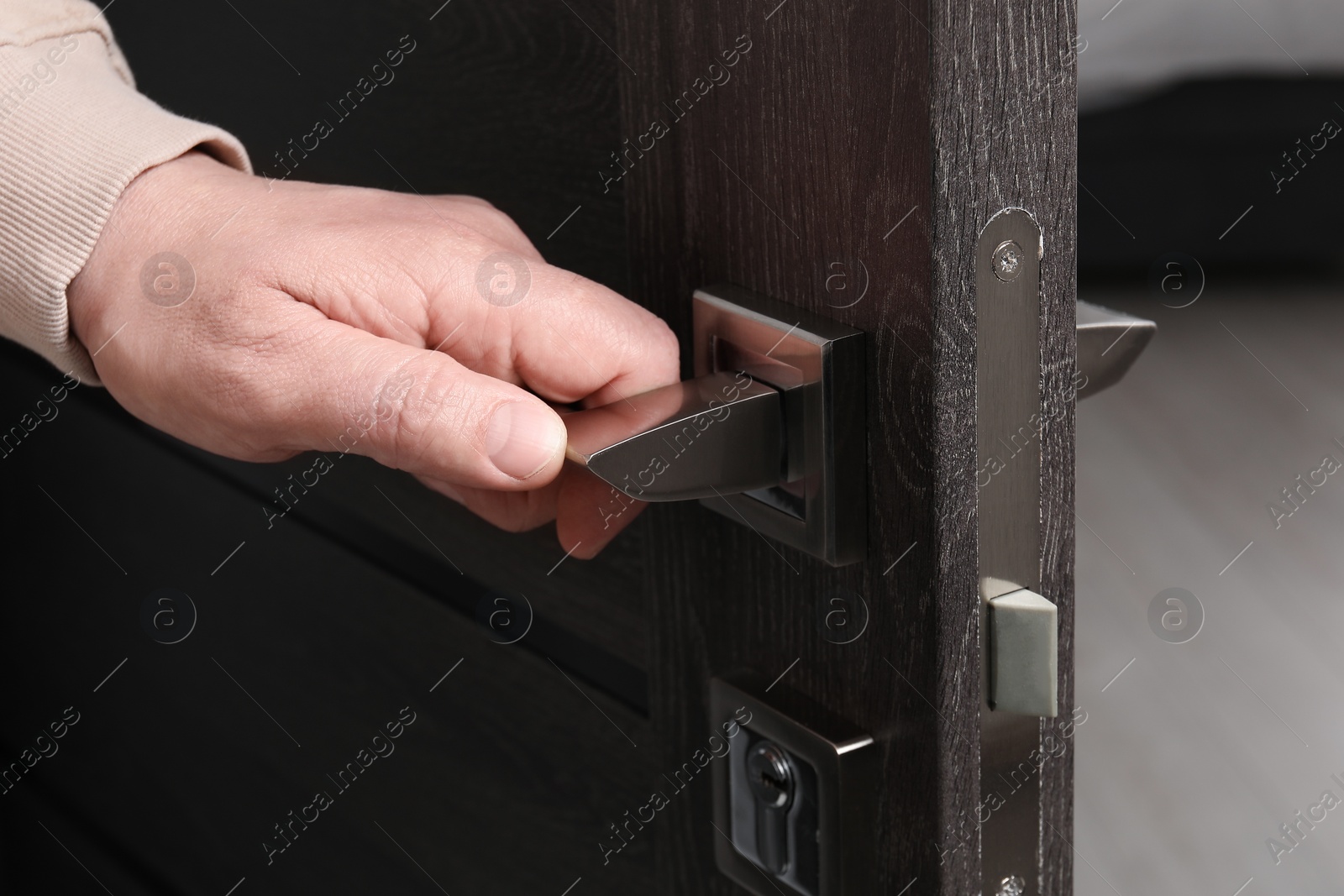 Photo of Man opening wooden door indoors, closeup of hand on handle