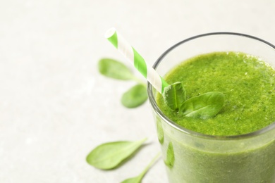 Green juice and fresh spinach leaves on light grey table, closeup. Space for text