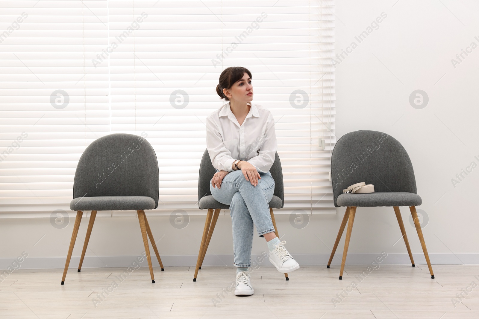 Photo of Woman sitting on chair and waiting for appointment indoors