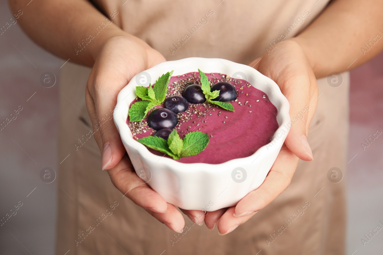 Photo of Woman holding bowl with tasty acai smoothie, closeup