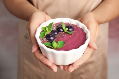 Woman holding bowl with tasty acai smoothie, closeup