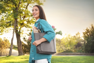 Photo of Young woman with leather shopper bag in park