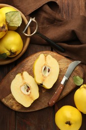 Photo of Tasty ripe quince fruits, peeler and knife on wooden table, flat lay