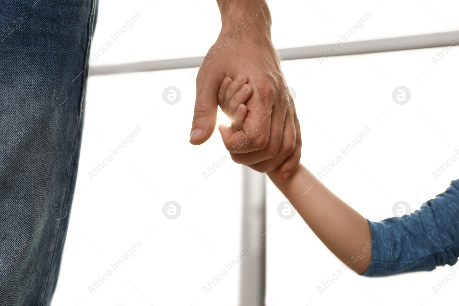 Photo of Father holding hands with his child indoors, closeup. Happy family