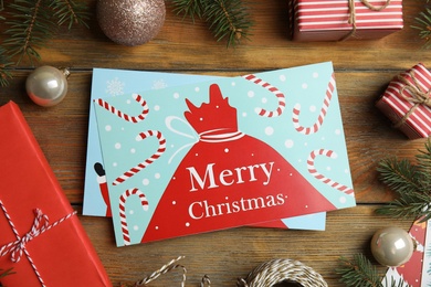 Flat lay composition with Christmas cards and festive decor on wooden background