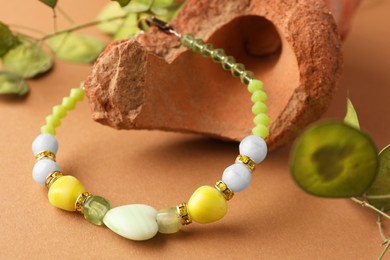 Photo of Stylish presentation of beautiful bracelet with gemstones on light brown background, closeup