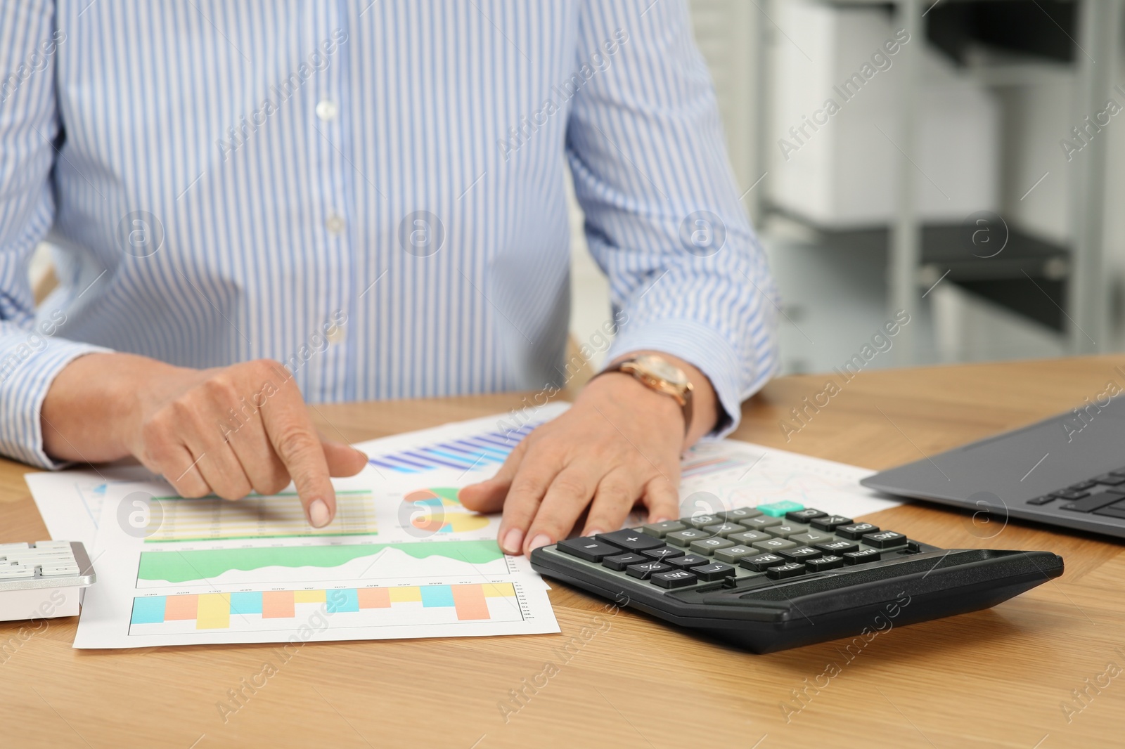 Photo of Accountant using calculator at wooden desk in office, closeup