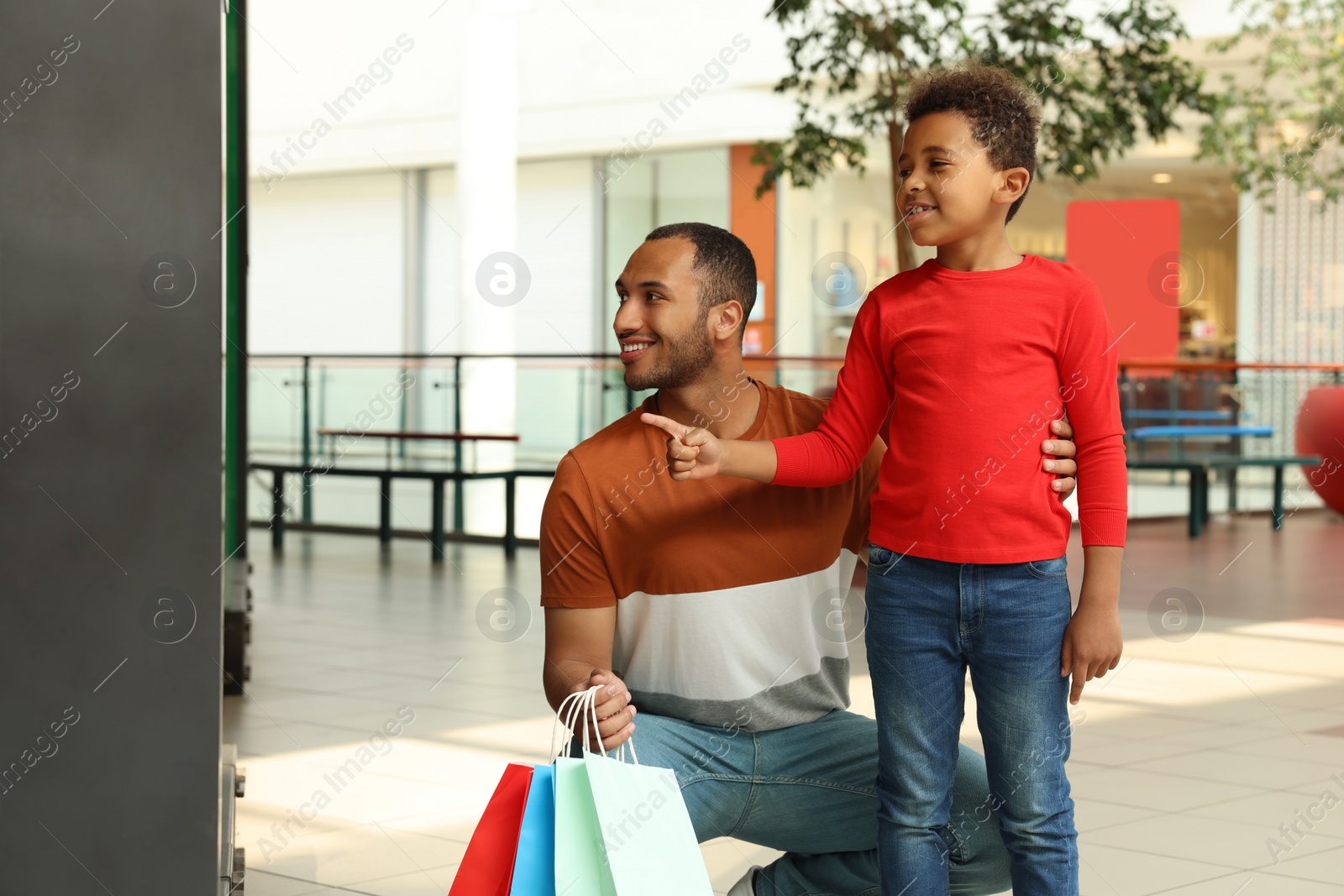 Photo of Family shopping. Happy father and son with colorful bags in mall