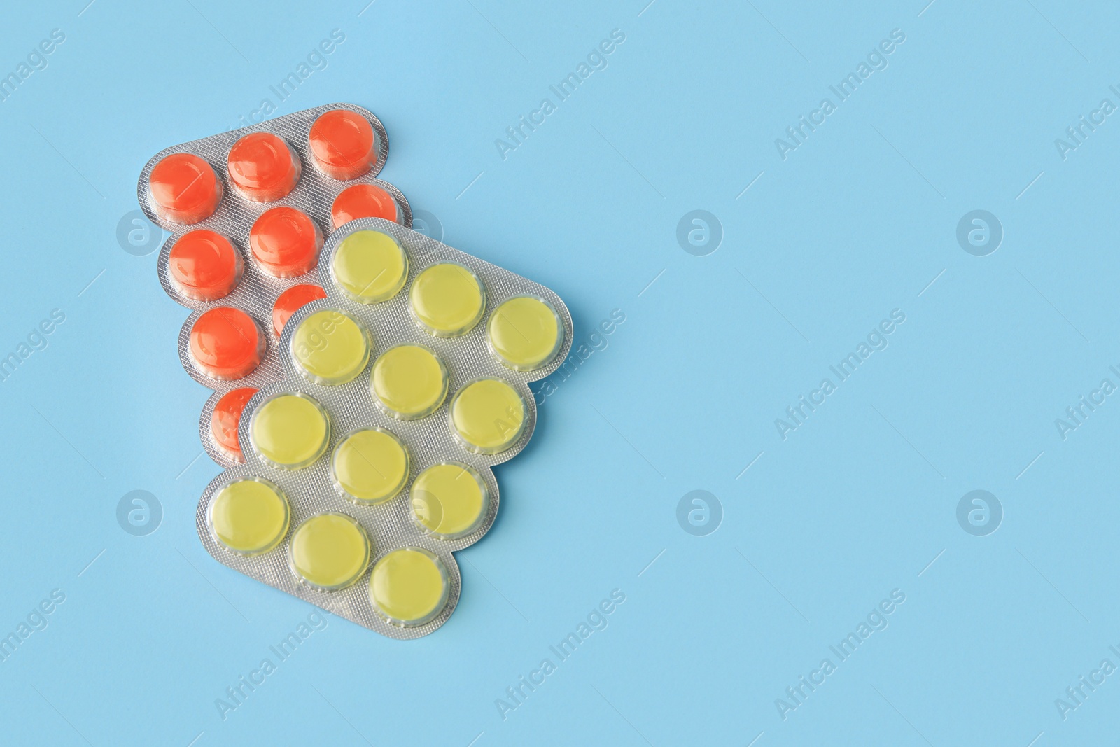 Photo of Blisters with cough drops on light blue background, flat lay. Space for text