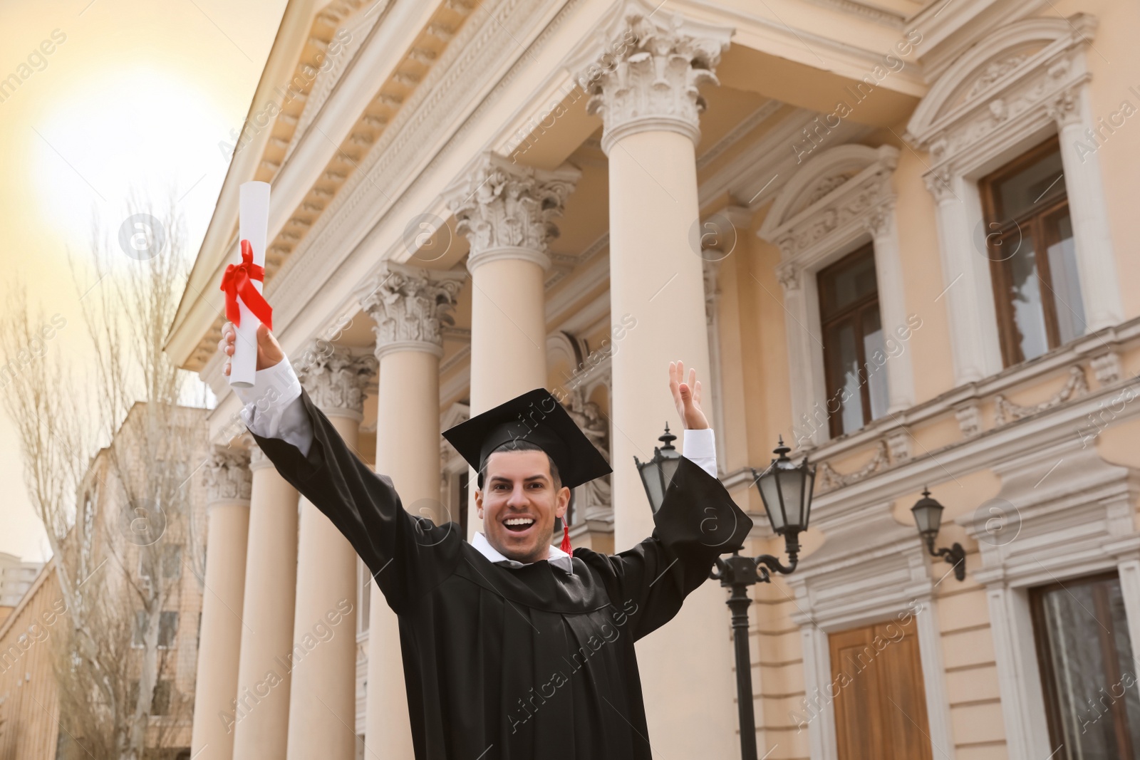 Photo of Happy student with diploma after graduation ceremony outdoors