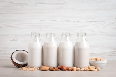 Photo of Different nut milks in glass bottles on white table