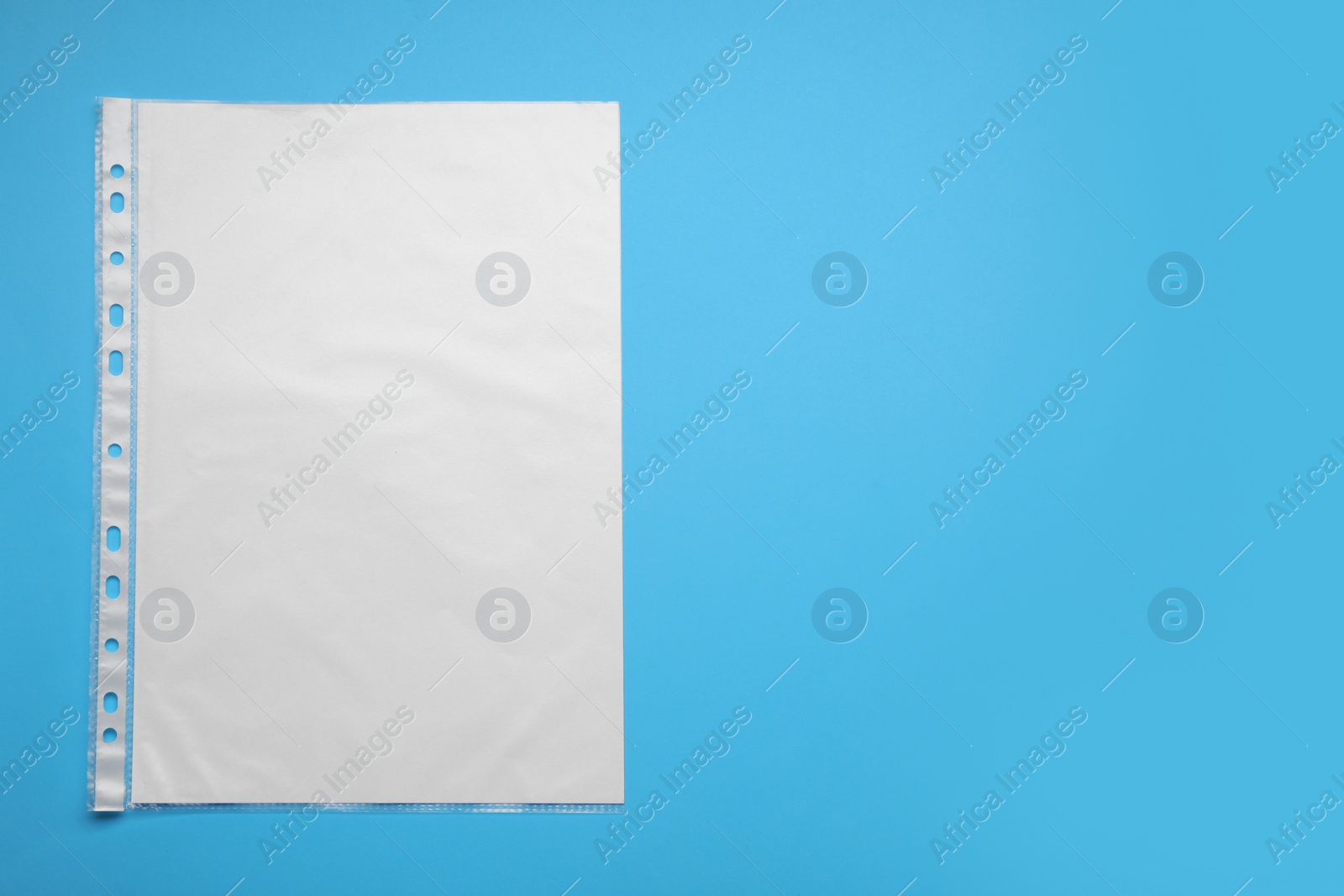 Photo of Punched pocket with paper sheet on light blue background, top view. Space for text