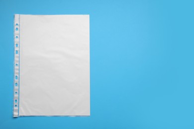 Photo of Punched pocket with paper sheet on light blue background, top view. Space for text