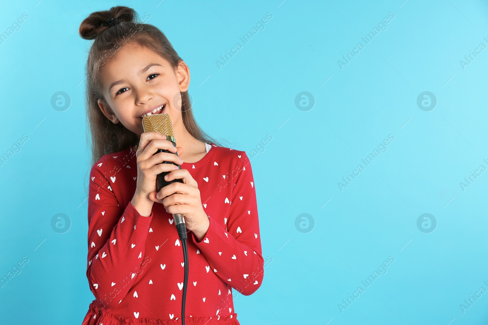 Photo of Cute funny girl with microphone on color background. Space for text