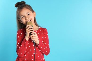 Cute funny girl with microphone on color background. Space for text