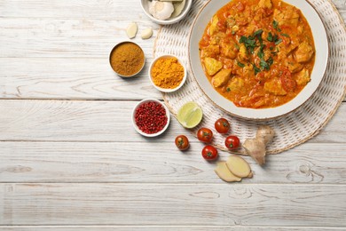 Delicious chicken curry and ingredients on wooden table, flat lay. Space for text