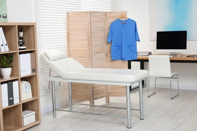 Photo of Modern medical office with doctor's workplace and examination table in clinic