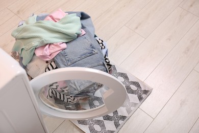 Laundry basket with clothes on floor near washing machine in bathroom, above view. Space for text