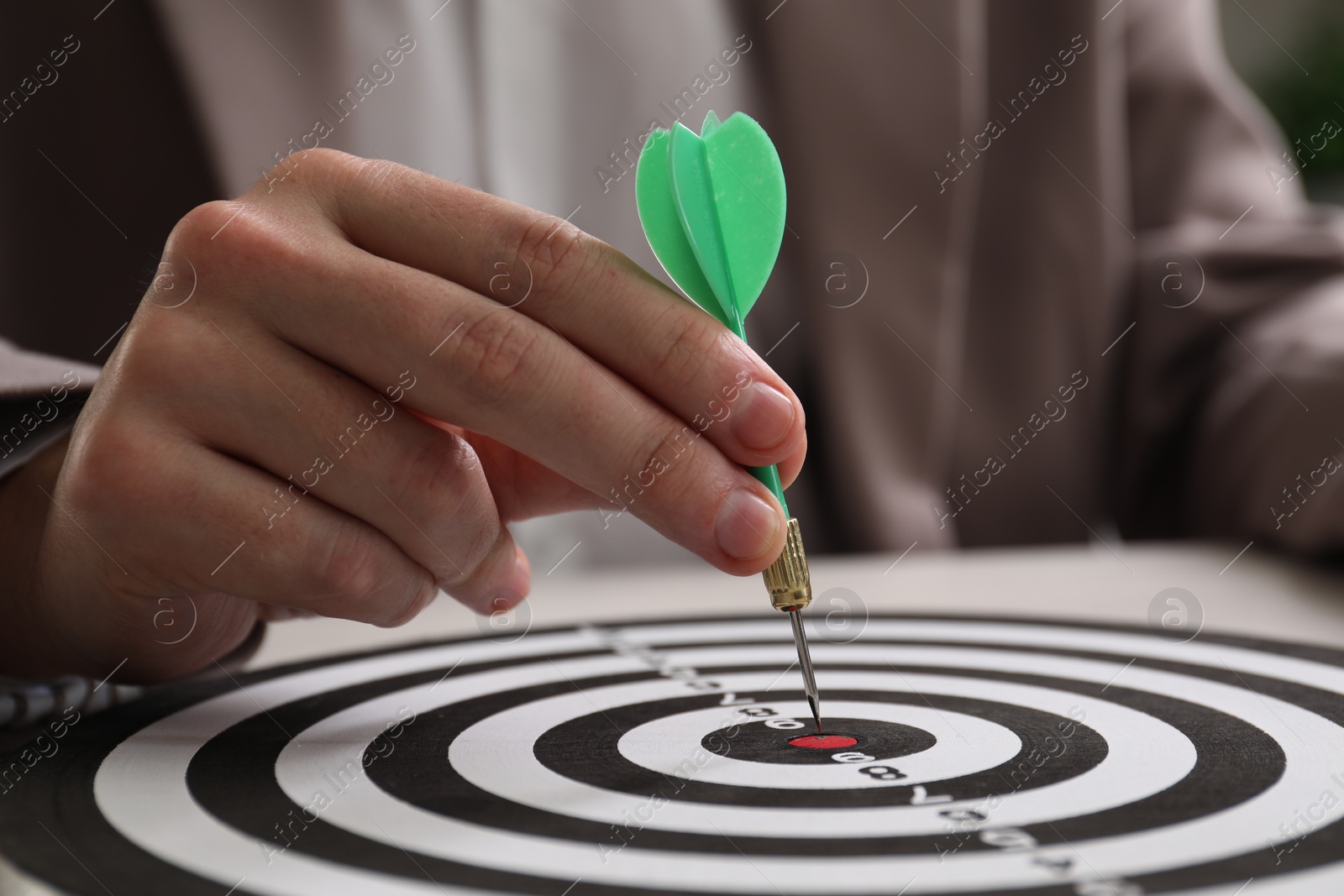 Photo of Business targeting concept. Man with dart aiming at dartboard at table, closeup