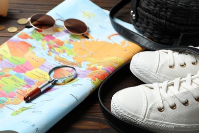 World map and accessories on wooden background, closeup. Travel during summer vacation