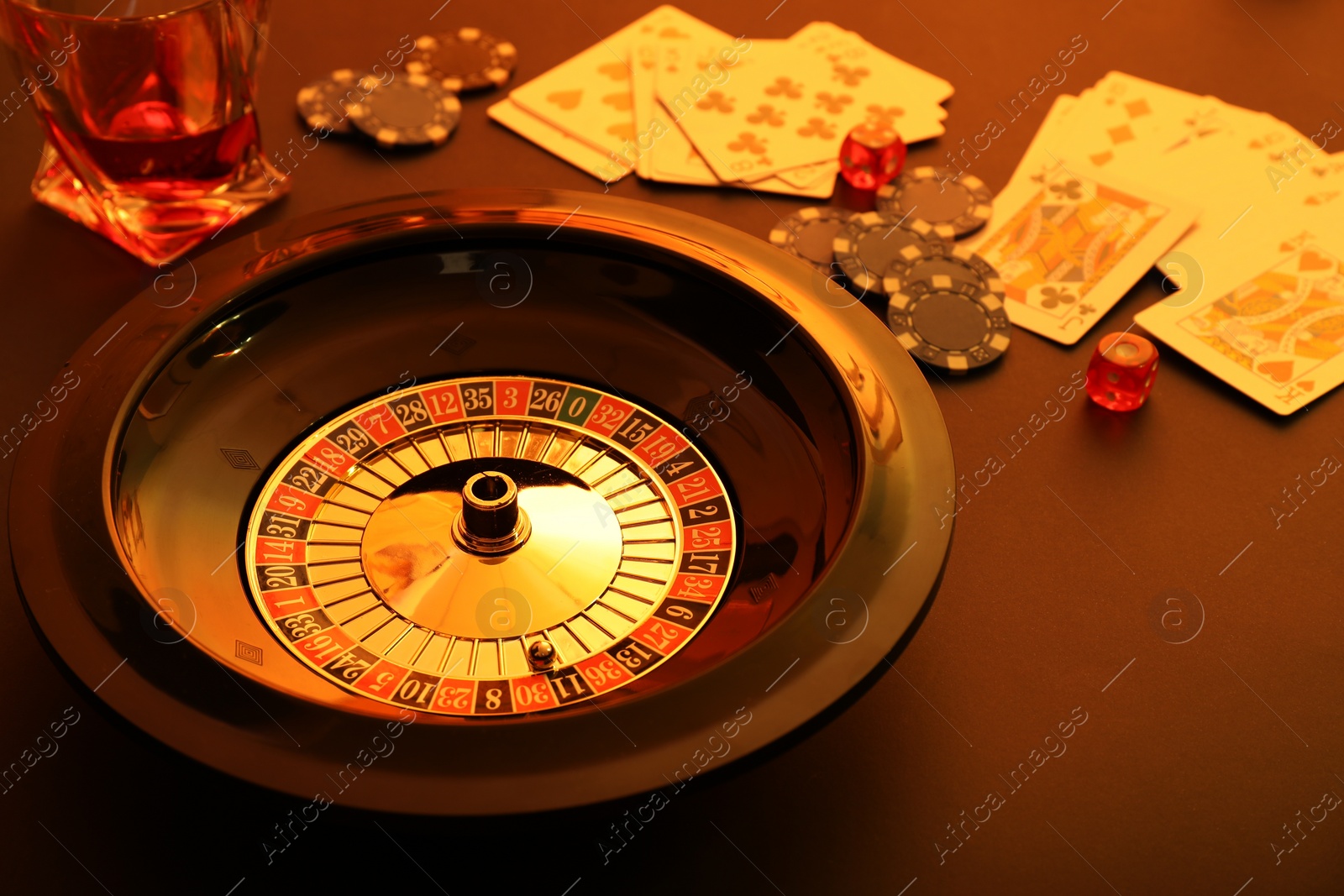 Photo of Roulette wheel, playing cards and chips on table, closeup. Casino game