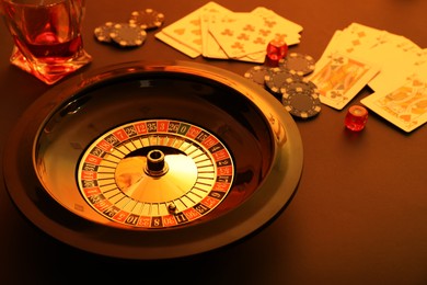 Photo of Roulette wheel, playing cards and chips on table, closeup. Casino game