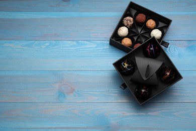 Boxes of tasty chocolate candies on light blue wooden table, flat lay. Space for text